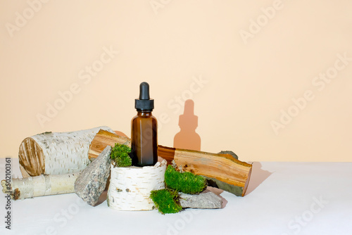 Glass dropper brown bottle cosmetic oil,cream,essential,serum on wooden stump podium,bark tree,green moss with hard shadow.natural organic eco spa cosmetics,medicine.herbal homeopathic products mockup