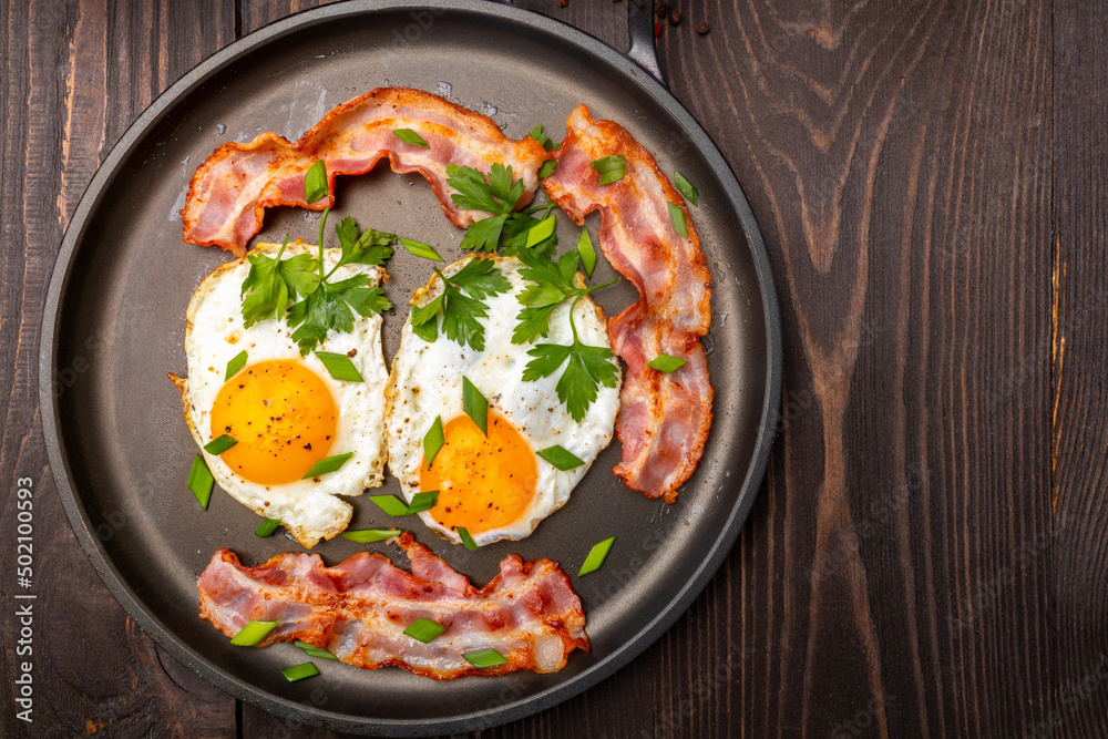 fried eggs with bacon and herbs on a frying pan top view fried eggs with bacon and herbs on a frying pan top view