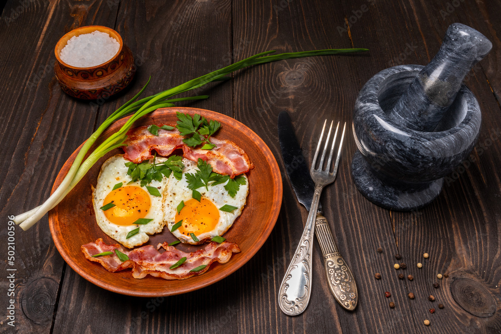 fried eggs with bacon and herbs on a clay plate