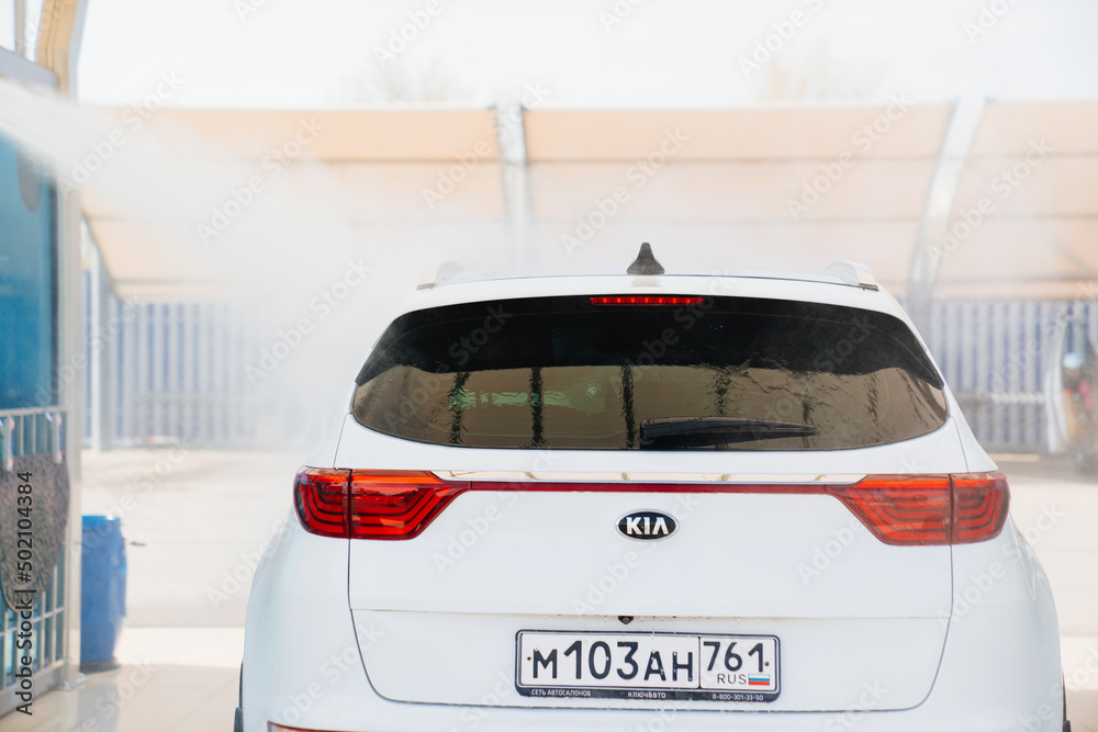 selfservice car wash. a person washes the car from a hose. kia Stock Photo Adobe Stock