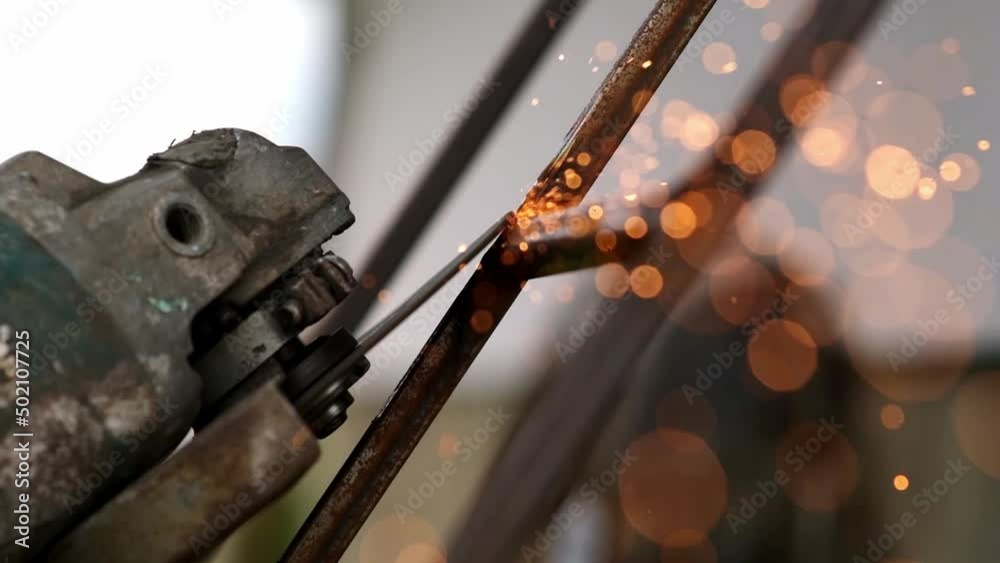 Grinding works with smooth equipment for steel metals, iron, sparks in a heavy industry plant close-up indoors. Welding of thermal parts by a professional worker using a grinder. Slow motion
