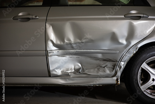 car after a car accident with a crooked and demolished door for replacement through a insurance © losonsky