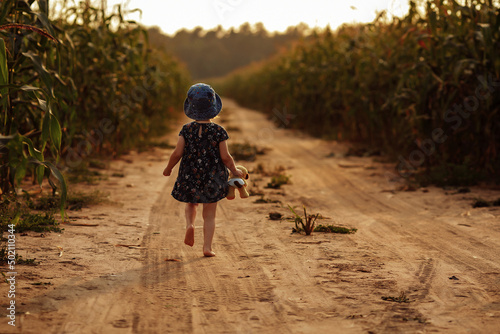 Charming little girl runs along a field road.