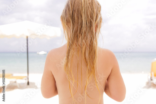 Child's long hair on the beach. Wet hair close up image. Hair damage due to salty ocean water and sun, summertime hair care concept.  © triocean