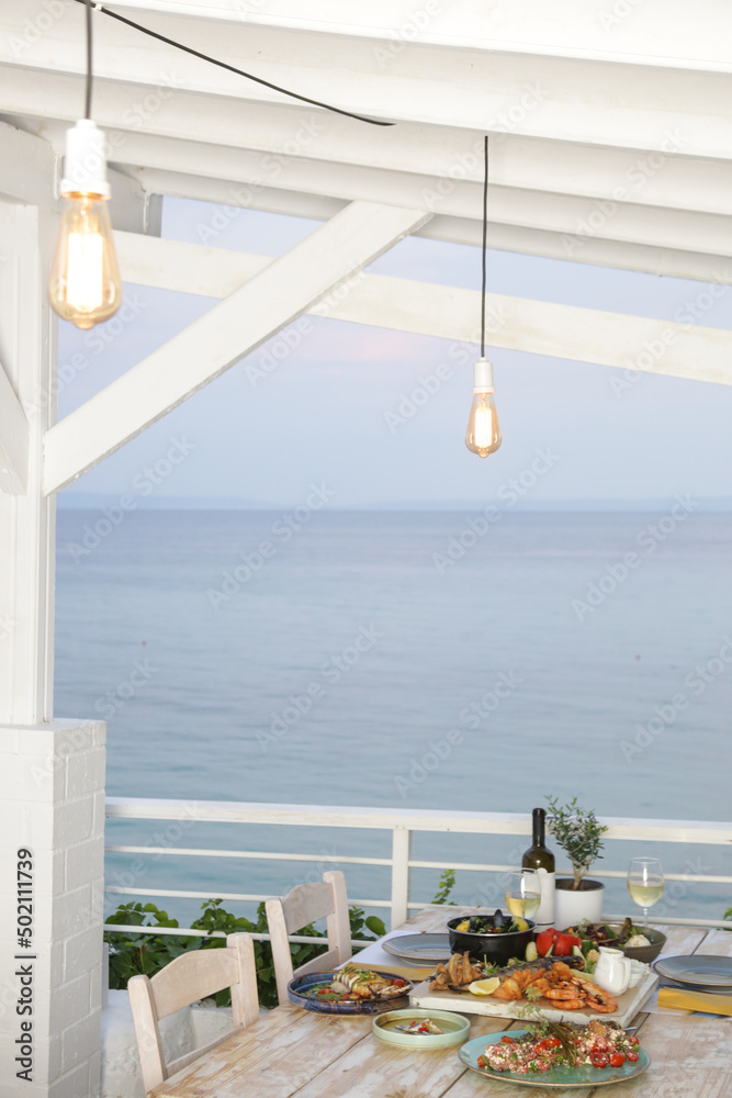 Fototapeta premium Table full of seafood and vegetable dishes with sea horizone in the background