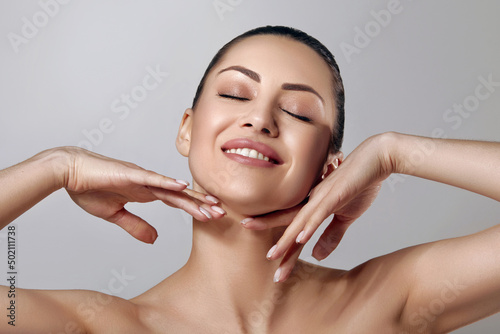 Skin care. Woman with beauty face touching healthy facial skin portrait. Beautiful smiling girl model with natural makeup touching her skin.