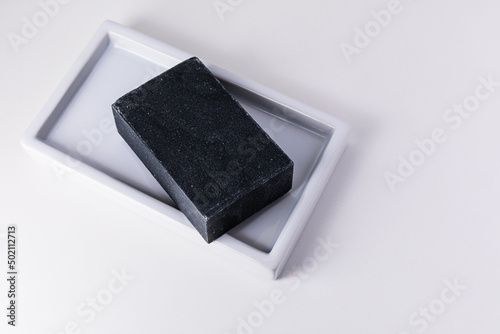 Natural organic hand cut charcoal soap bar on white background with copy space.
