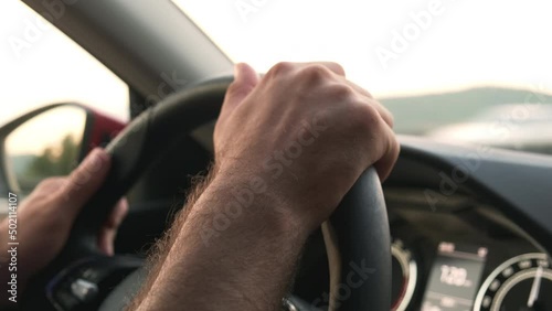 Wallpaper Mural Driver holds leather steering wheel of car speeding past trees in highland. Young man hands drive car along highway at bright sunset extreme closeup Torontodigital.ca