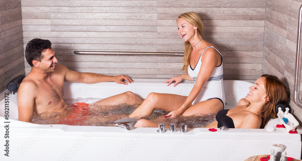 Obraz premium Man with two girlfriends are enjoying of relax in jacuzzi in spa.