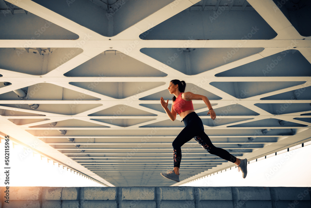 Young fitness woman runner running in the city