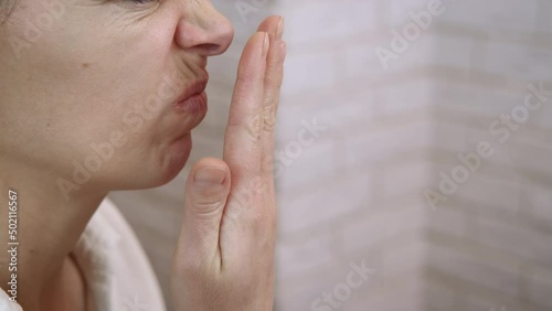 Spray for bad smell. A woman feel bad smell from her mouth and use spray at home. photo