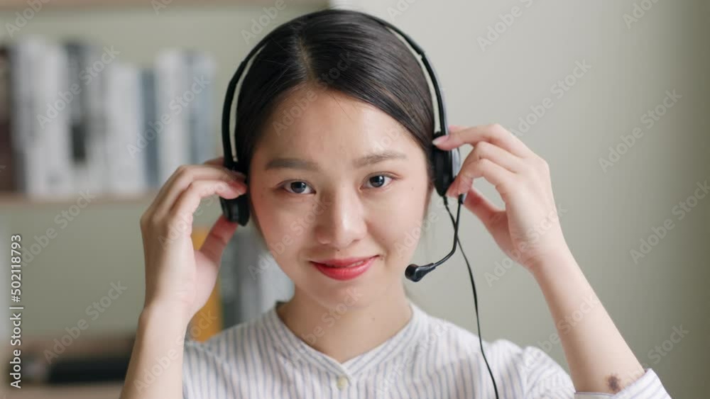 Close up of Young Asian woman, call center, customer service wearing headphone and smiling. Look at camera Close up of Young Asian woman, call center, customer service wearing headphone and smiling. Look at camera