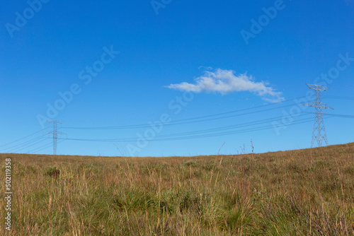 Electric power tower in the countryside, blue sky background.