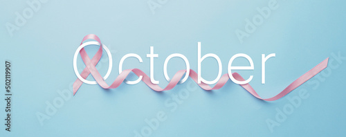 Pink ribbon and word OCTOBER on light blue background. Breast cancer awareness month