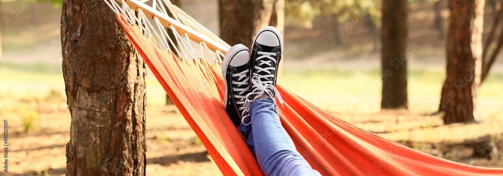 Legs of young woman relaxing in hammock outdoors - obrazy, fototapety, plakaty 