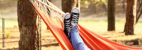 Legs of young woman relaxing in hammock outdoors photo