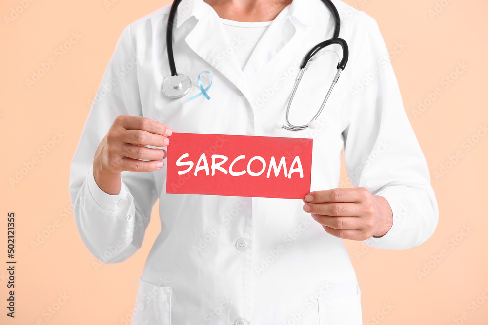 Doctor holding paper with word SARCOMA on light color background Doctor holding paper with word SARCOMA on light color background