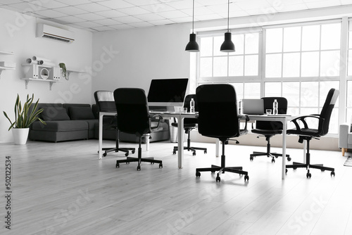 Interior of light office with table, chairs and sofa