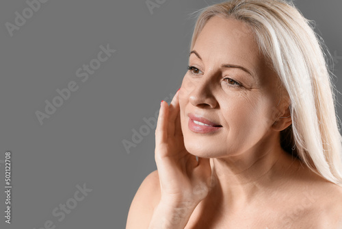 Mature blonde woman with healthy skin on dark background  closeup