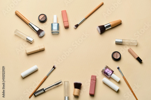 Frame made of makeup brushes and cosmetic products on beige background