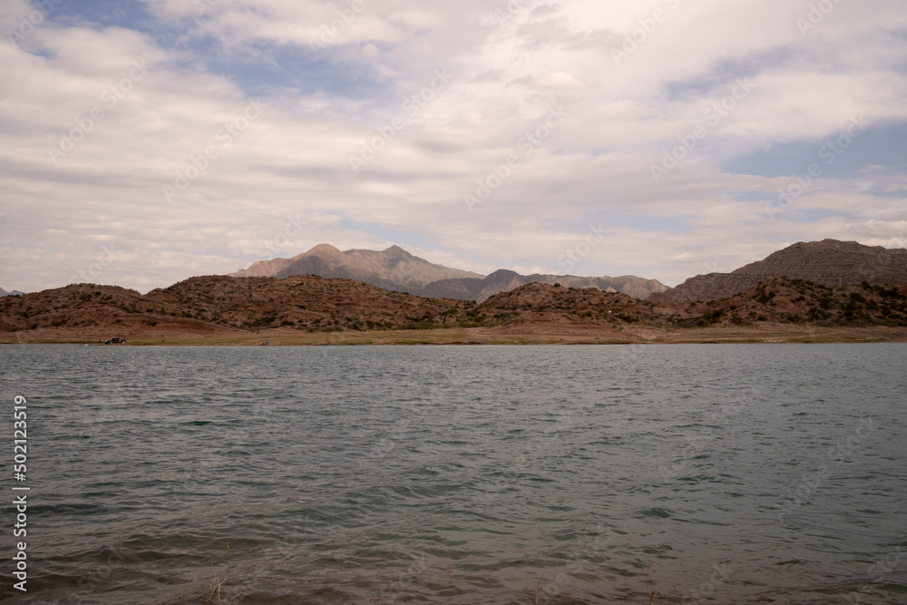 View of the reservoir in Potrerillos, Mendoza. The arid environment, turquoise glacier water lake and Andes mountains in the background. View of the reservoir in Potrerillos, Mendoza. The arid environment, turquoise glacier water lake and Andes mountains in the background.