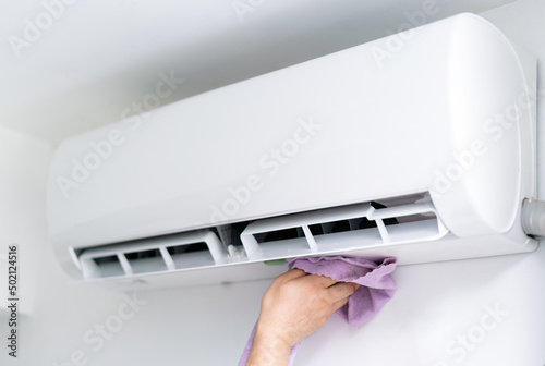 man cleaning the air conditioner with cloth at home