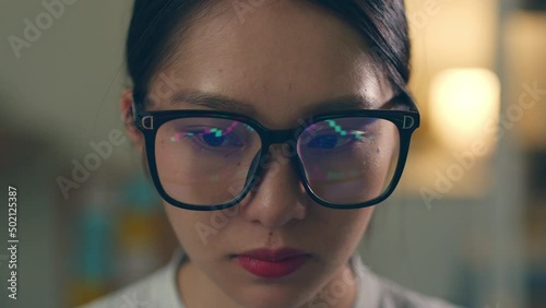 Stock trading woman wearing eyeglasses looking at computer screen reflecting in glasses analyzing stock trading graph. Close up of eyes refection