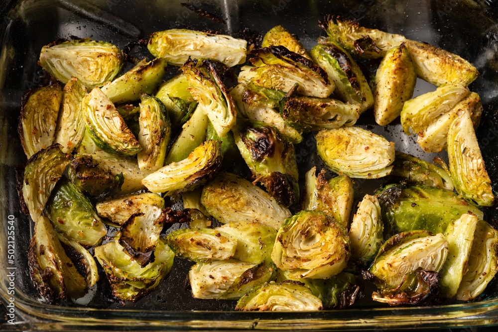 Brussels sprouts roasted in the oven with spices, salt, black pepper and Italian herbs in a glass tray. Vegetarian home cooking concept. Brussels sprouts roasted in the oven with spices, salt, black pepper and Italian herbs in a glass tray. Vegetarian home cooking concept.