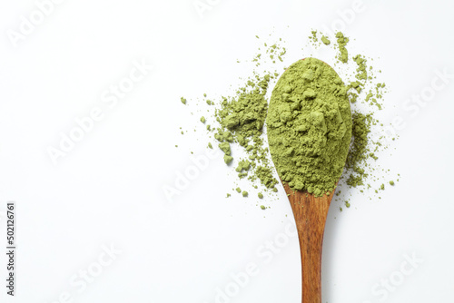 Matcha green tea powder in a wooden spoon on white background