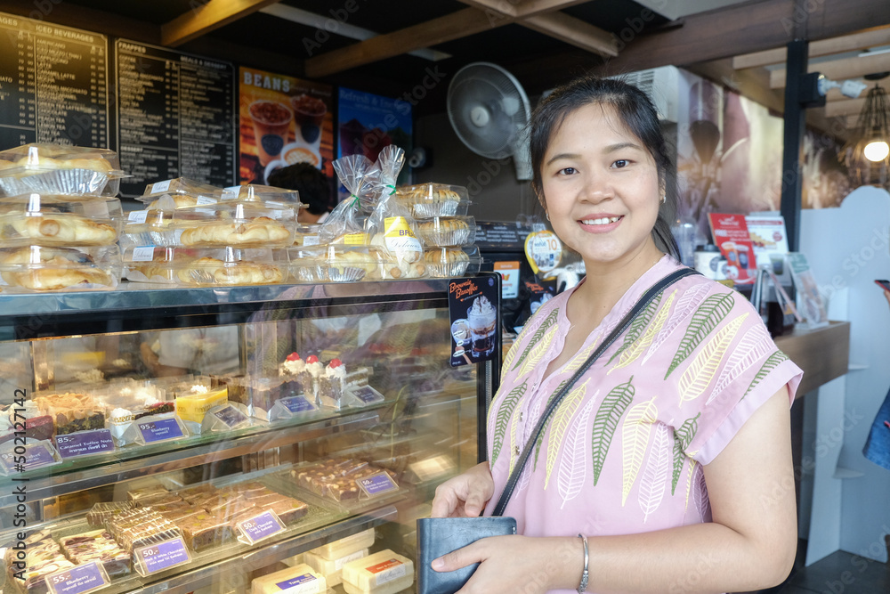 Young asian woman choosing sweet products at grocery supermarket shopping at pastry shop.
