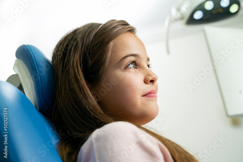 Beautiful little girl sitting in dentist chair, side view