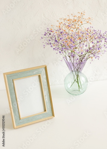 Frame mockup , modern vase with  flowers on white background.Neutral color. Photo frame, poster template on white wall background. Scandinavian interior. Copy space.