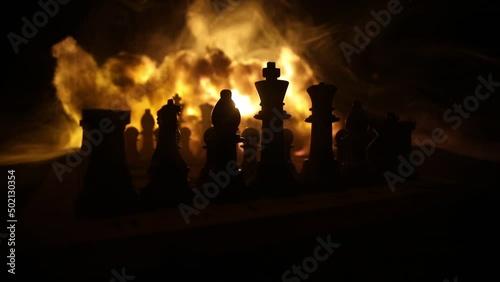 Chess board game concept of business ideas and competition or war theme. Chess figures on a dark background of explosion and fire clouds. Selective focus
