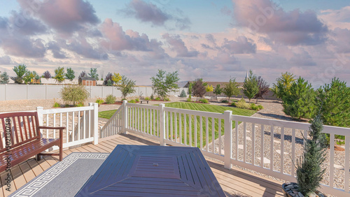 Panorama Puffy clouds at sunset Deck of a house with potted pine tree near the fire pit table an