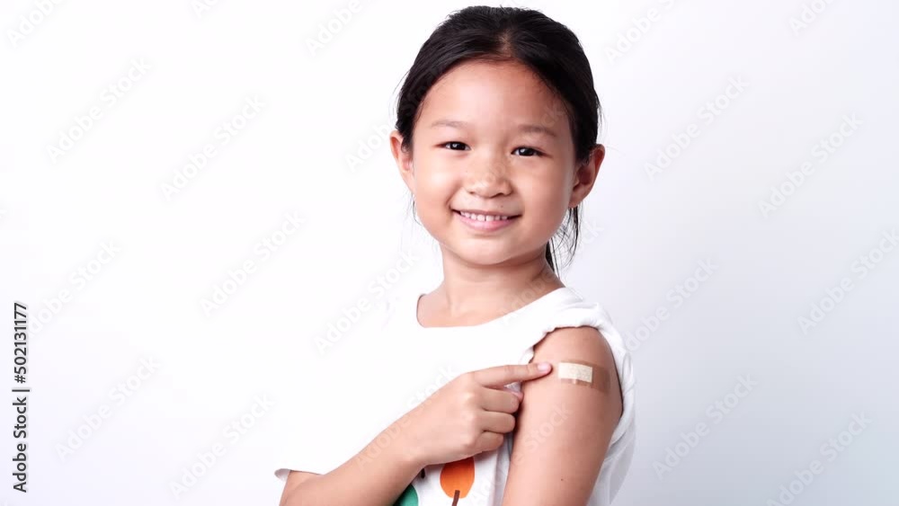 Vaccine concept. Happy Asian little child girl smiling, showing arm with plaster bandage after received, getting COVID-19 vaccine injection. Concept of inoculation, vaccinate, campaign, COVID19, Flu Vaccine concept. Happy Asian little child girl smiling, showing arm with plaster bandage after received, getting COVID-19 vaccine injection. Concept of inoculation, vaccinate, campaign, COVID19, Flu