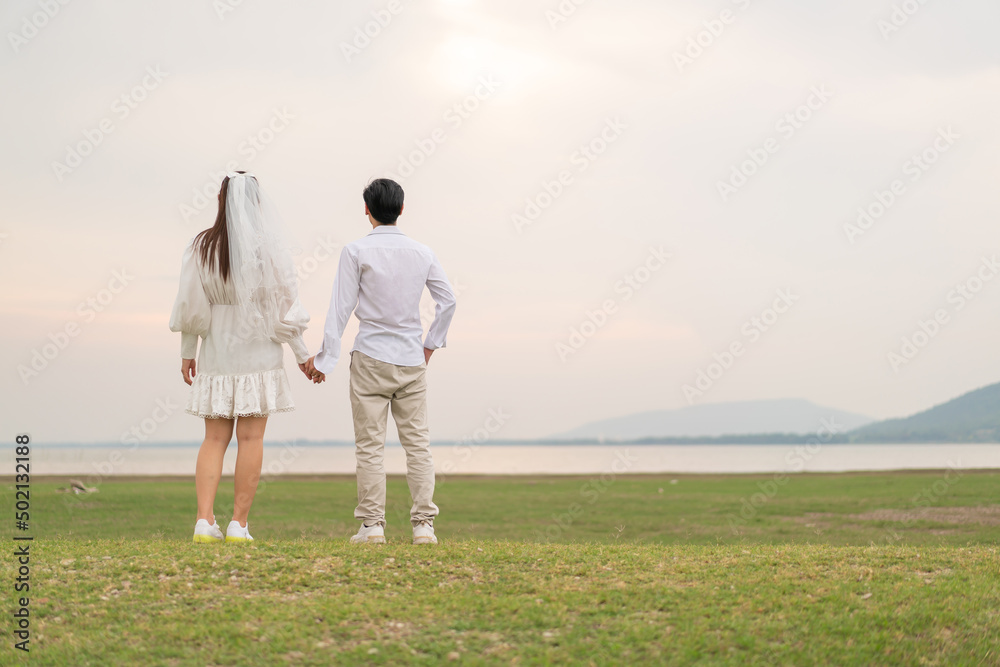 Happy young Asian couple in bride and groom clothing Happy young Asian couple in bride and groom clothing