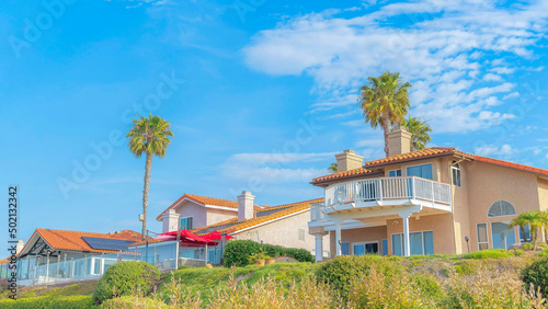 Panorama White puffy clouds Large residential houses and palm trees on top of a hill at Southern California