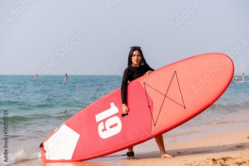 Canvas Print Beautiful woman wearing bikini  standing up paddle standing up paddling sup board in ocean sea is extreme water sport in holiday summer vacation