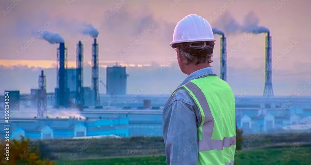 back view Senior engineer wearing helmet and life jacket on factory background back view Senior engineer wearing helmet and life jacket on factory background