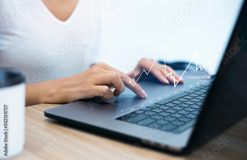 Business analytics concept with businesswoman using computer laptop working with digital screen, stock market chart and graphs at blurry background, Double exposure, Focus on hand using laptop