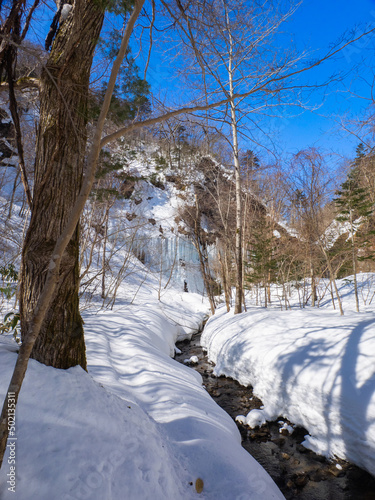 Icefalls seen beyond a snow-covered stream (Shiraoi, Hokkaido, Japan) photo