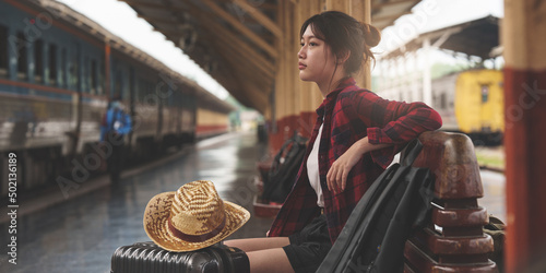 Young traveler woman looking for friend planning trip at train station. Summer and travel lifestyle concept. photo