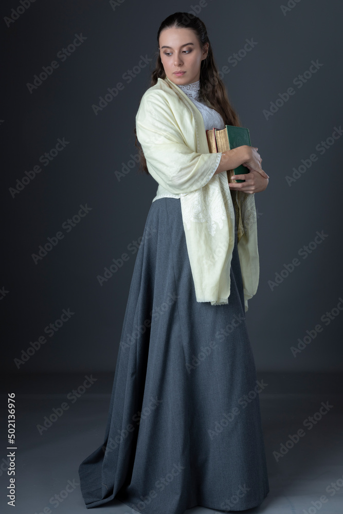 A Victorian or Edwardian woman with long hair standing and holding books A Victorian or Edwardian woman with long hair standing and holding books