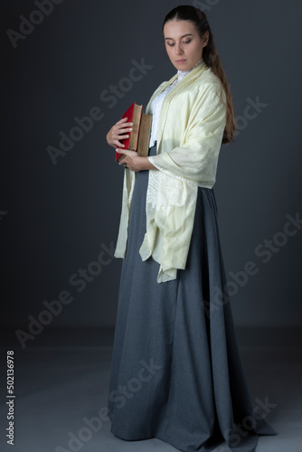 A Victorian or Edwardian woman with long hair standing and holding books