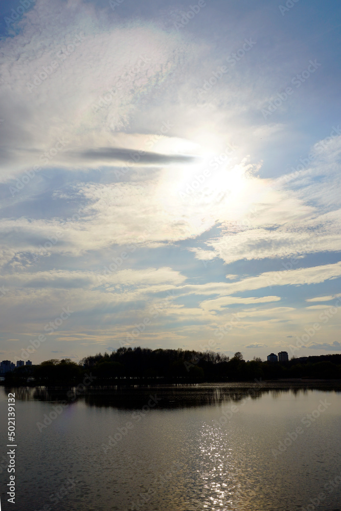 Spring mood. The first leaves on the willows. Sunset over the lake and glare on the water. Warm evening Spring mood. The first leaves on the willows. Sunset over the lake and glare on the water. Warm evening