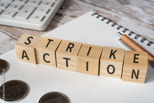 ストライキのイメージ｜「STRIKE ACTION」と書かれた積み木、電卓、ノート、コイン