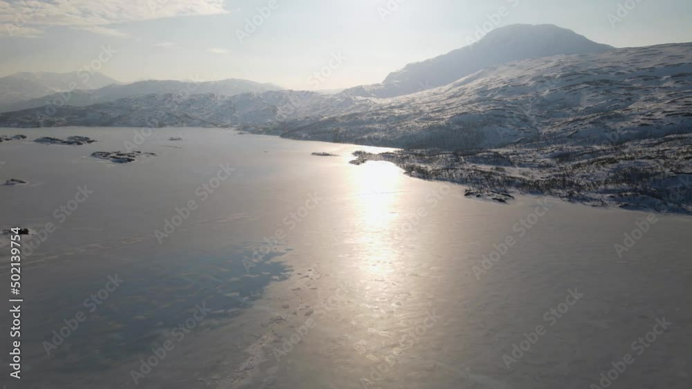 Aerial 4k tilt shot of a frozen lake, the sun reflecting of its surface on a beautiful winters day Aerial 4k tilt shot of a frozen lake, the sun reflecting of its surface on a beautiful winters day