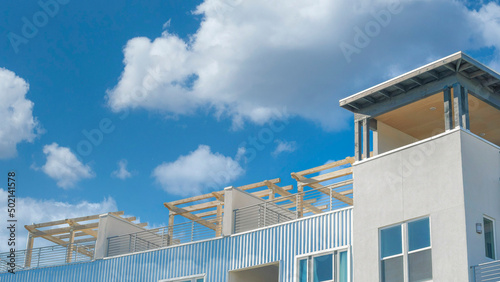 Panorama White puffy clouds Residential building exterior with pergola roofs at the rooftop © Jason
