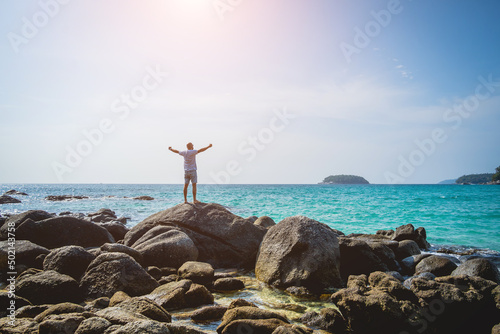 Young man relaxing on the beach while standing on an stones