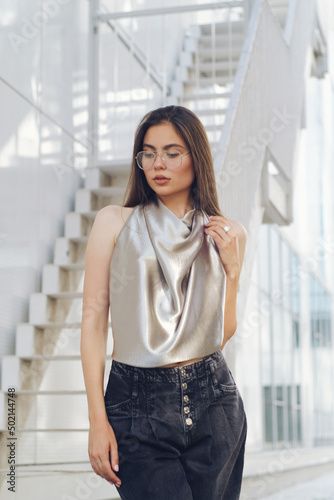 Long hair woman in a summer blouse and jeans posing in an urban setting 